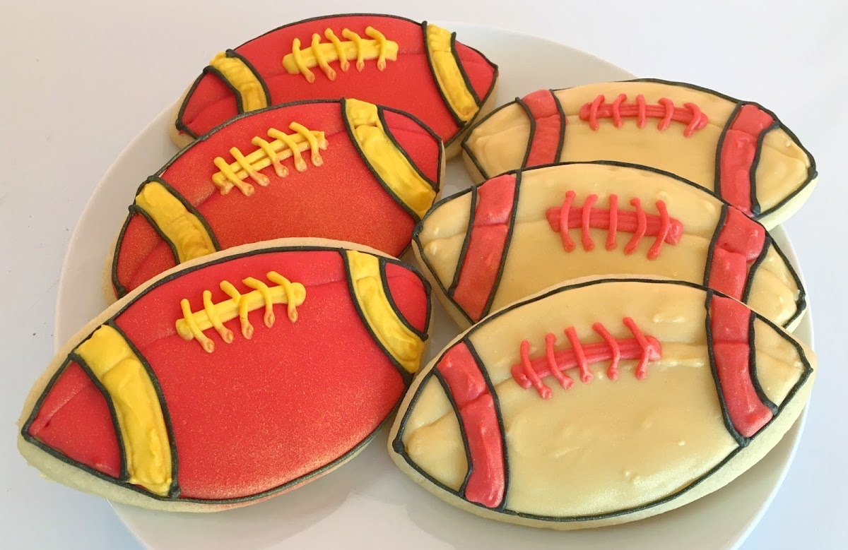 Decorated football sugar cookies in red, gold, and cream