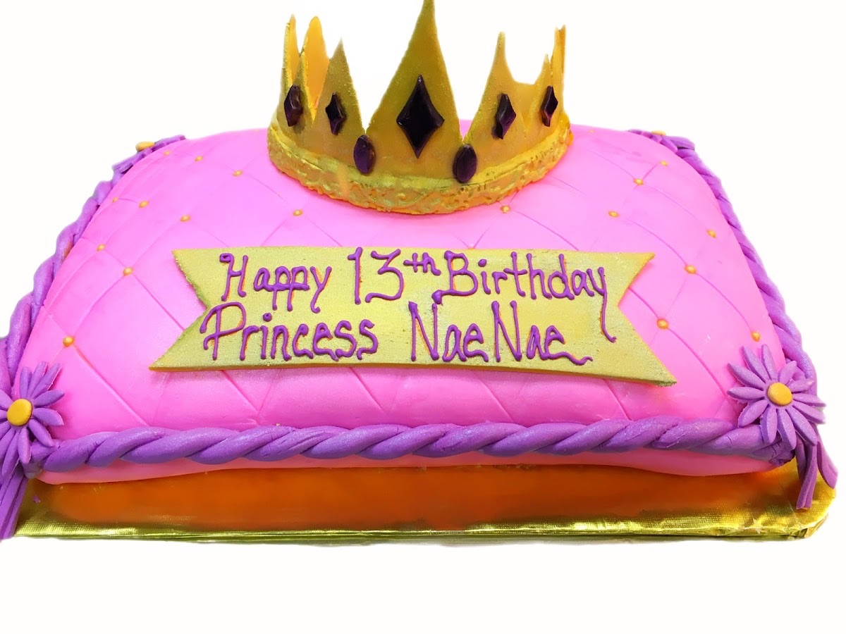 Pink celebration cake topped with a gold crown, made at Final Kourse Bakery